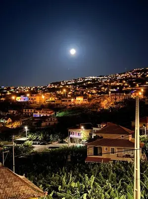 a view of a city at night with the moon at Luxury Haven: Heated Pool, AC & Sun in Ponta do Sol