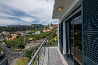 a balcony with a view of a city at Luxury Haven: Heated Pool, AC & Sun in Ponta do Sol