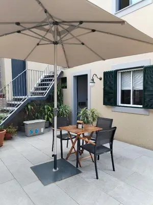 a table and chairs under an umbrella on a patio at Casa do Favinha in Machico