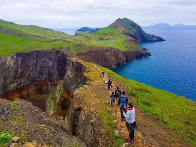a group of people walking on a cliff near the ocean at Casa do Favinha in Machico