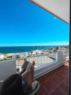a woman laying on a balcony reading a book at Casa Amar- Vista panorâmica in Luz