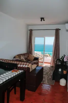 a living room with a couch and a balcony with the ocean at Casa Amar- Vista panorâmica in Luz