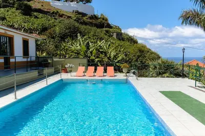 a swimming pool with chairs and a house at Hikers Haven in Faial