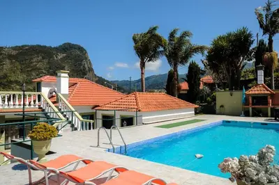 a house with a swimming pool and palm trees at Hikers Haven in Faial