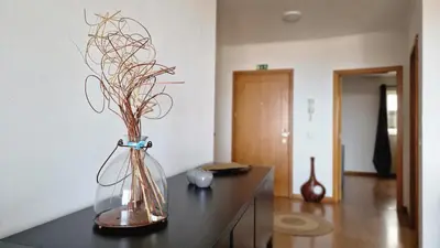 a vase with branches in it sitting on a table at Azenha Apartment by LovelyStay in Caniço