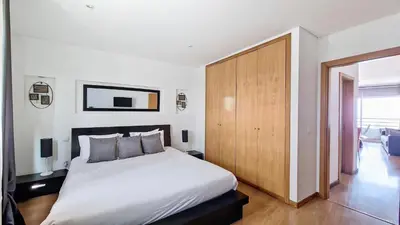 a bedroom with a white bed and a wooden cabinet at Azenha Apartment by LovelyStay in Caniço