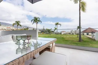 a balcony with a table and chairs and palm trees at SeaLaVie Apartment in Funchal