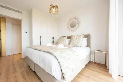 a white bedroom with a large white bed and a chandelier at SeaLaVie Apartment in Funchal