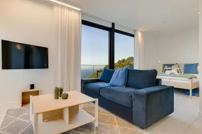 a living room with a blue couch and a bed at Mar Yam View by Atlantic Holiday in Arco de São Jorge