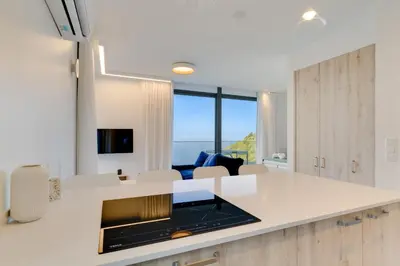 a kitchen with white countertops and a living room at Mar Yam View by Atlantic Holiday in Arco de São Jorge