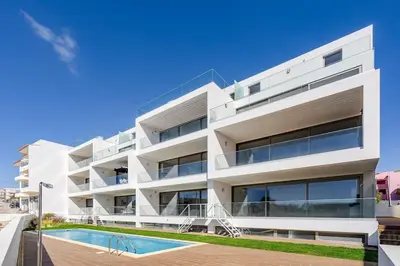 a white apartment building with a swimming pool at Gaivota Ocean view & 5min walk beach in Luz