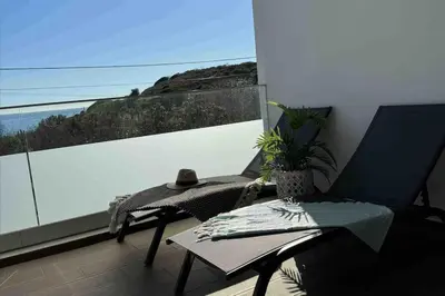 a balcony with a chair and a table and a window at Gaivota Ocean view & 5min walk beach in Luz