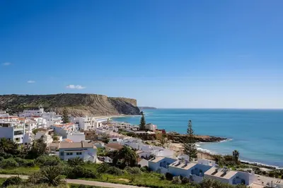 a group of white houses on a hill next to the ocean at Gaivota Ocean view & 5min walk beach in Luz