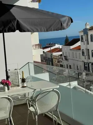 a table and chairs on a balcony with an umbrella at Gaivota Ocean view & 5min walk beach in Luz
