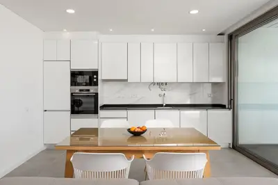 a kitchen with a wooden table and white cabinets at Gaivota Ocean view & 5min walk beach in Luz