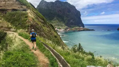 a woman walking on a trail near the ocean at Maiata Beach House by Holiday Rental Madeira in Porto da Cruz