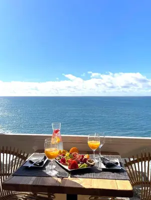 a table with a plate of food and two glasses of juice at Boutique Hotel Jardim Do Mar in Jardim do Mar