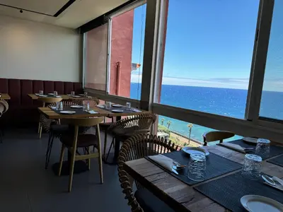 a restaurant with tables and chairs and a view of the ocean at Boutique Hotel Jardim Do Mar in Jardim do Mar