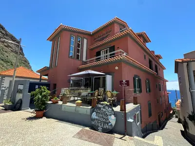 a red building with a restaurant on a street at Boutique Hotel Jardim Do Mar in Jardim do Mar