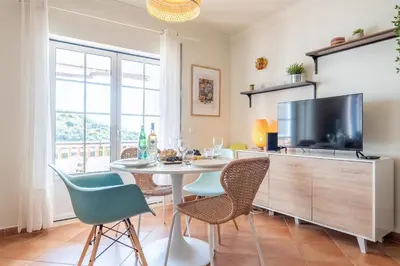 a dining room with a table and chairs and a tv at Arrifana Sunset & Surf in Aljezur