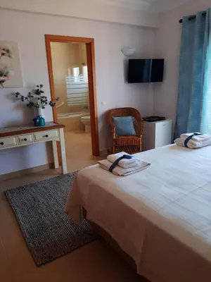 a bedroom with a bed and a desk and a chair at Lucie Lime GuestHouse in Luz