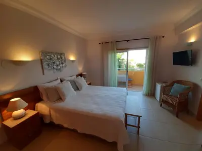 a bedroom with a large white bed and a balcony at Lucie Lime GuestHouse in Luz