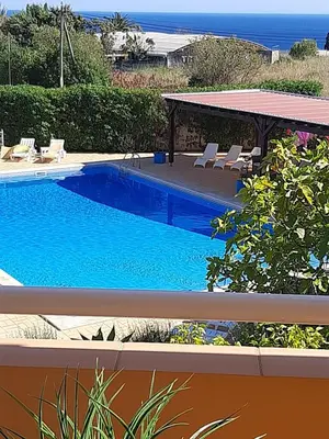 a swimming pool with chairs and the ocean in the background at Lucie Lime GuestHouse in Luz