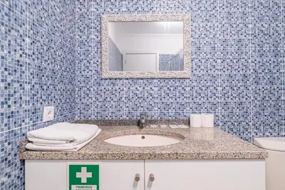 a blue tiled bathroom with a toilet and a mirror at Old Town T1 Apartment in Funchal