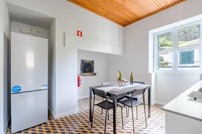 a kitchen with a table and a refrigerator at JMF House in São Vicente