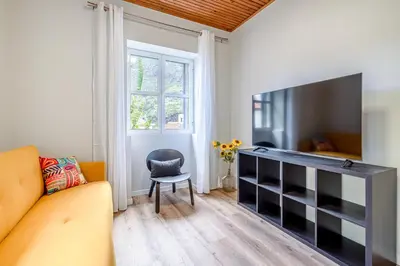 a living room with a couch and a television at JMF House in São Vicente