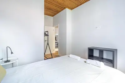 a bedroom with a white bed and a tv at JMF House in São Vicente