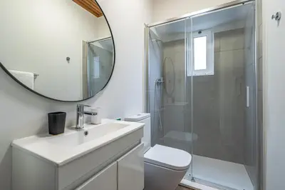 a bathroom with a shower and a sink and a mirror at JMF House in São Vicente