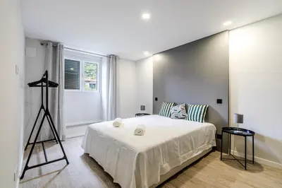 a bedroom with a large white bed and a window at JMF House in São Vicente