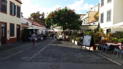 a person walking down a street in a town at Sao Thiago House Madeira in Funchal