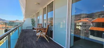 a balcony with a wooden table and chairs on it at Plaza Apartamento in Funchal