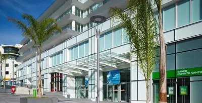 a large glass building with palm trees in front of it at Plaza Apartamento in Funchal