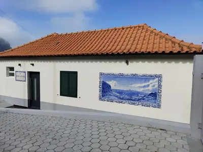 a white building with a tile roof and a window at Porto à Vista in Porto da Cruz