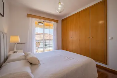 a bedroom with a large white bed with a window at Casa Flor do Campo in Calheta
