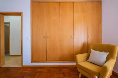 a living room with a chair and a cabinet at Casa Flor do Campo in Calheta