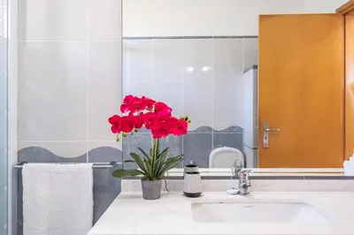 a bathroom with a sink with a vase with red flowers at Casa Flor do Campo in Calheta