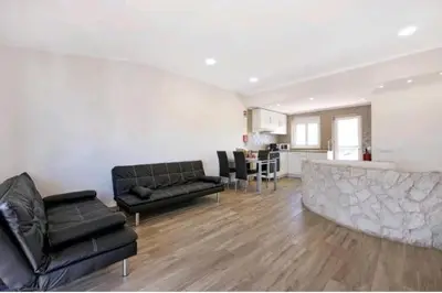 a living room with two black couches and a kitchen at Casa Serra e Mar in Luz