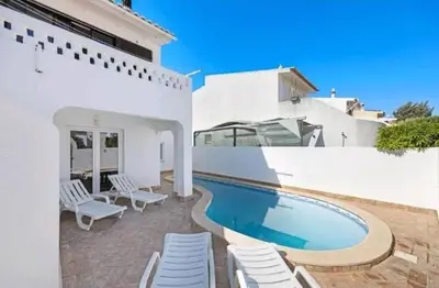 a white house with a swimming pool and white chairs at Casa Serra e Mar in Luz