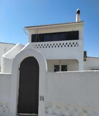 a white building with a gate and a lighthouse at Casa Serra e Mar in Luz