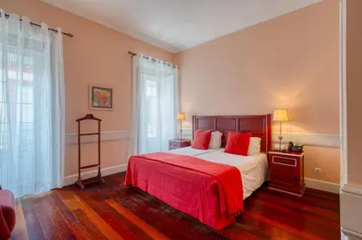 a bedroom with a large bed with a red blanket at O Cantinho da Mariazinha by Amazing Madeira in Funchal
