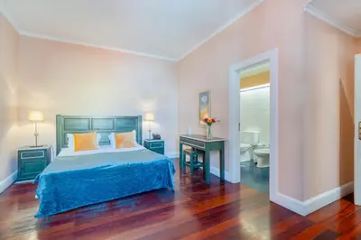 a bedroom with a bed and a table and a bathroom at O Cantinho da Mariazinha by Amazing Madeira in Funchal