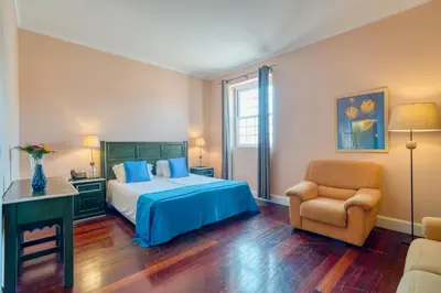 a bedroom with a bed and a chair at O Cantinho da Mariazinha by Amazing Madeira in Funchal