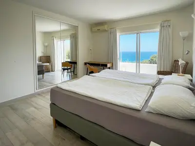 a bedroom with a large bed with a view of the ocean at 414 Casa Colina Mar in Salema