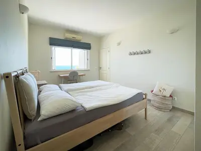 a bedroom with a bed with white sheets and a window at 414 Casa Colina Mar in Salema