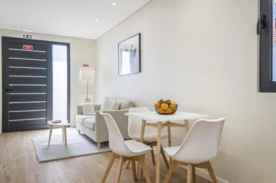 a living room with a table and chairs and a couch at Casa da Oliveira by Homie in Caniço