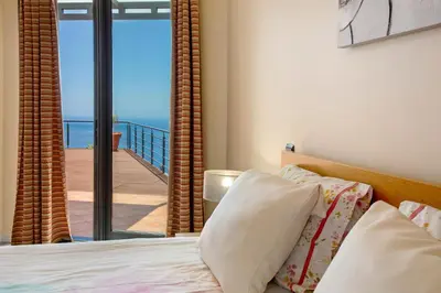 a bedroom with a bed with a view of a balcony at Sunparadise in Arco da Calheta